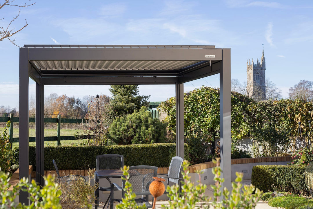 Pérgola de alumínio com lâminas abertas sobre área gourmet brasileira, tarde de verão com luz intensa e céu azul